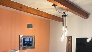 A living room with a brown sofa, a television, and a wooden ceiling. - Cozy Condo near Plaza with view from covered balcony (Santa Fe)