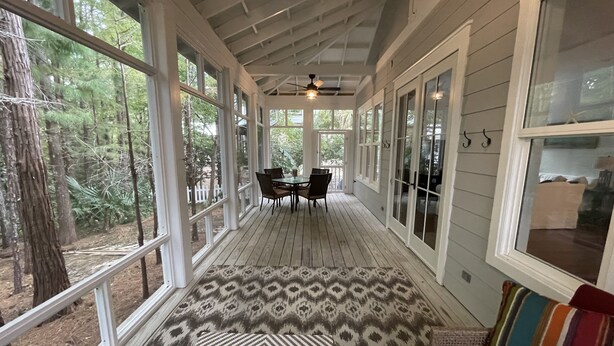 A covered porch with a dining table and chairs, large windows, and a patterned rug. - NEW FALL RATES! Picturesque Cottage Retreat in Cassine Village, Seagrove Beach (Santa Rosa Beach)