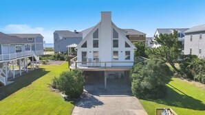 A two-story house with a balcony, a driveway, and a lawn. - Heron Pointe: Oceanwalk home with waterway views and just a short stroll to the (Oak Island)