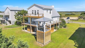A two-story house with a balcony and a covered outdoor area. - Heron Pointe: Oceanwalk home with waterway views and just a short stroll to the (Oak Island)