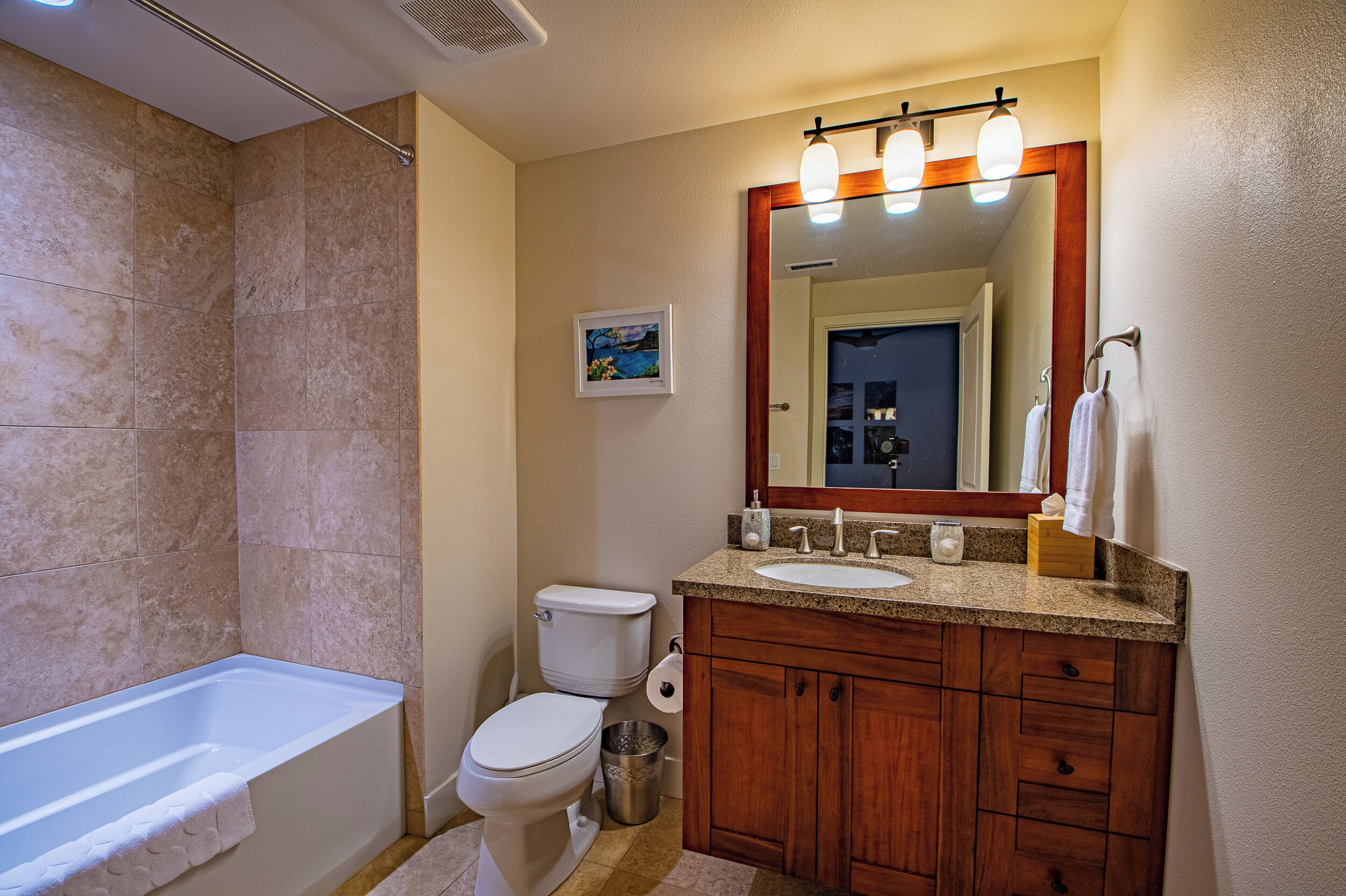 A bathroom with a bathtub, toilet, sink, and vanity with a mirror.
