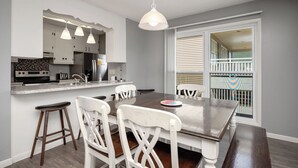 Uma cozinha moderna com armários brancos, uma mesa de jantar com cadeiras brancas e iluminação pendente.