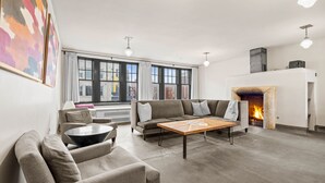 Een moderne woonkamer met een bank, een salontafel en een open haard.