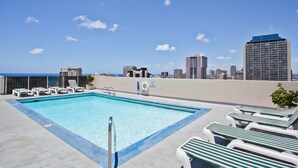 Una piscina sul tetto con lettini e uno skyline urbano sullo sfondo.