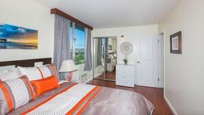 Una camera da letto con un letto, un comodino, una lampada, una cassettiera, uno specchio e vista sull'esterno.