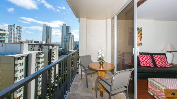 Un balcone con tavolo e sedie, un divano e vista sulla città.