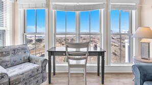 Una habitación con un amplio ventanal, una mesa de comedor con una silla, un sofá y una lámpara.