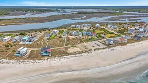 Vista aérea de una zona residencial costera con casas, una playa y un paisaje pantanoso.