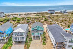 A beachfront property with multiple houses, a beach, and a clear view of the ocean.