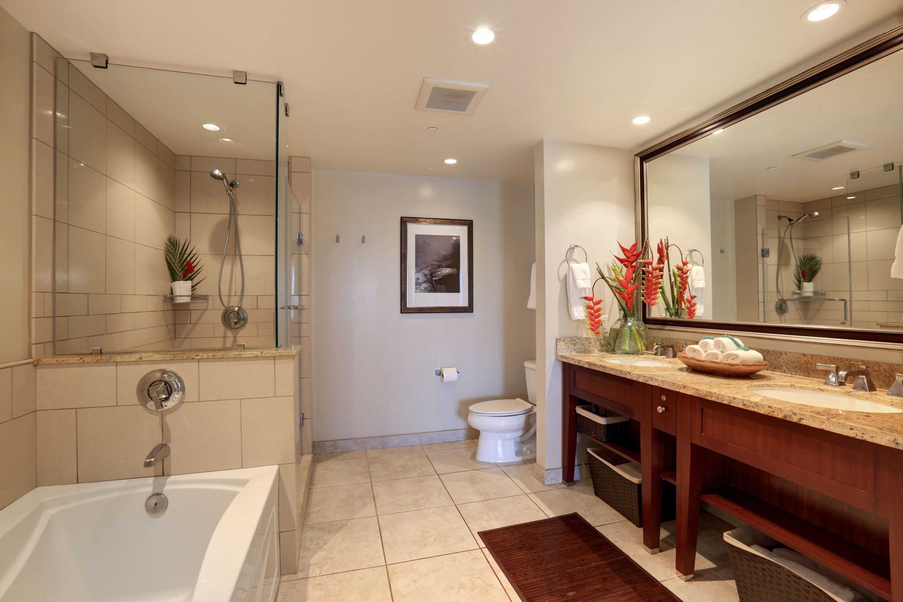 A modern bathroom with a bathtub, shower, toilet, and vanity with a large mirror.