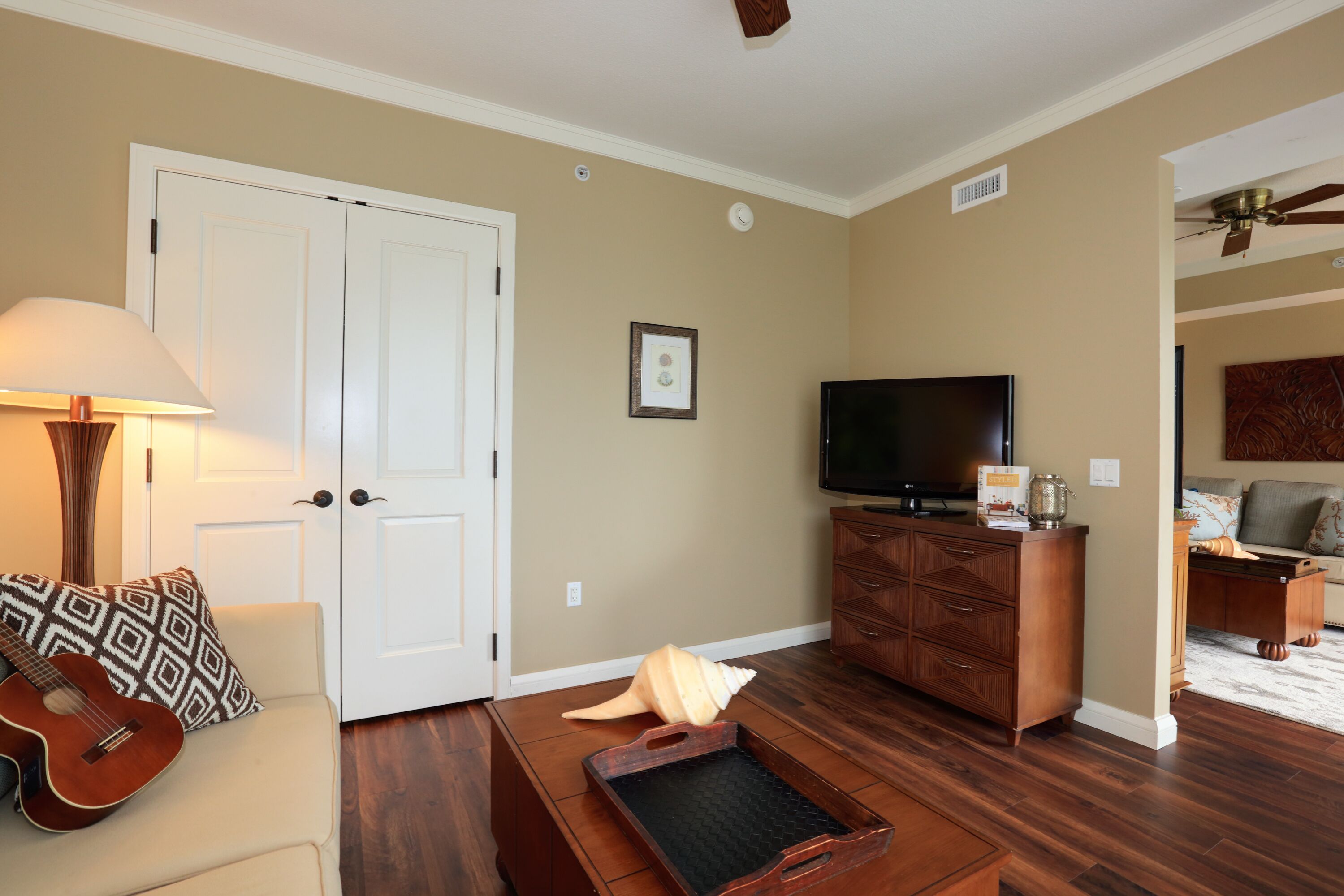 A living room with a sofa, a coffee table, a television, and a wooden cabinet.
