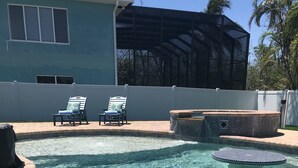 A clear swimming pool with a tiled deck, lounge chairs, and a hot tub area. - Decompress and Revitalize! Lose yourself in Paradise! (Fort Myers Beach)