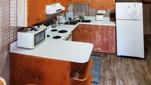 Una cucina rustica con pensili in legno, un forno a microonde, un fornello e una ventola a soffitto.