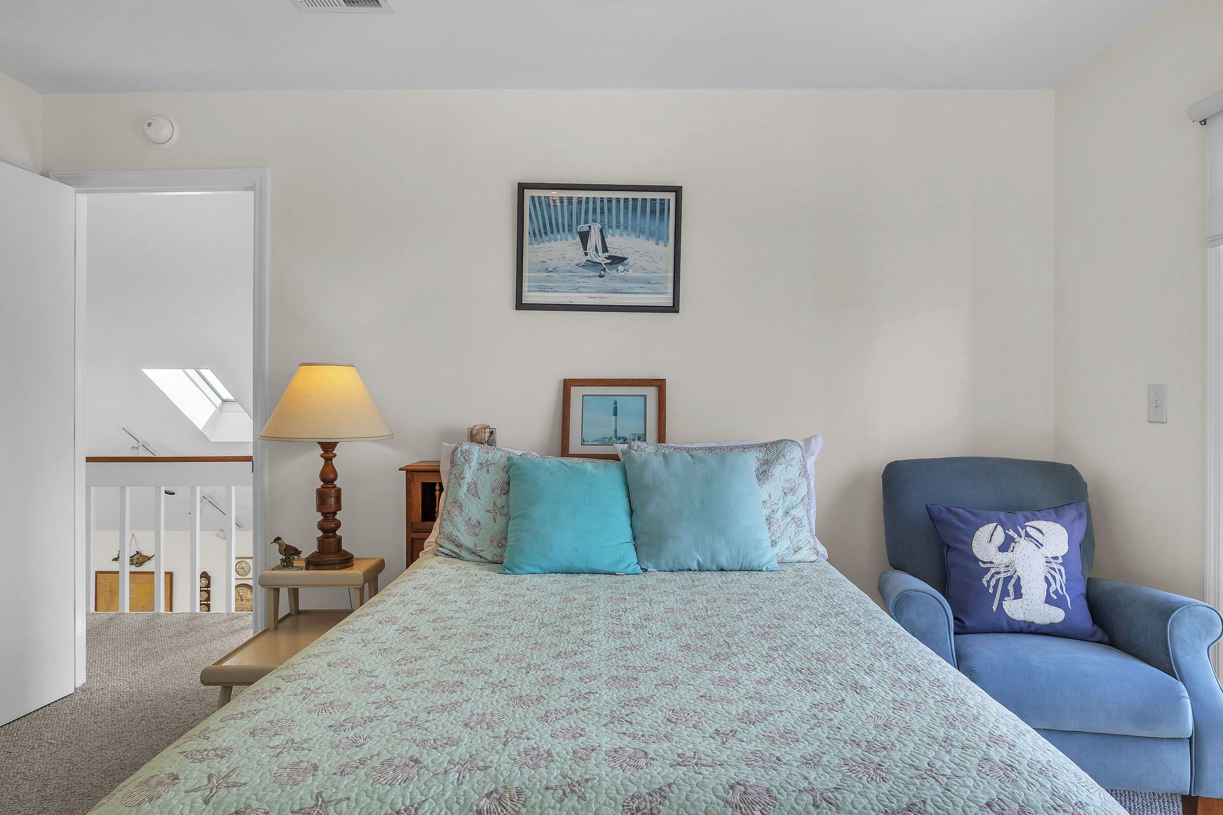 A bedroom with a bed, a chair, a lamp, and a painting on the wall.