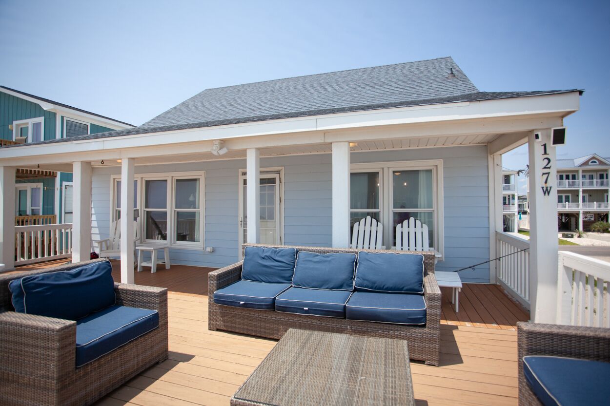Eine überdachte Terrasse mit Korbmöbeln und einem weißen Geländer.