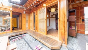 En traditionel japansk træbygning med tatamimåtter, skydedøre og et lille haveområde med chaussésten.