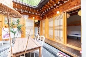 A traditional wooden room with tatami mats, a low wooden table, and a sliding door leading to a sleeping area. - Open Real Luxury Korean Hanok (Seoul)