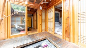 Et traditionelt japansk rum med tatamimåtter, en skydedør og et lille badeværelse med stenkar.