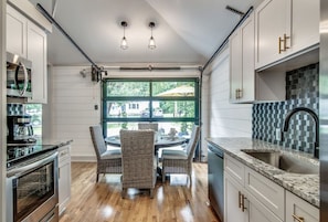 A kitchen with a dining table, chairs, and a view through a window.