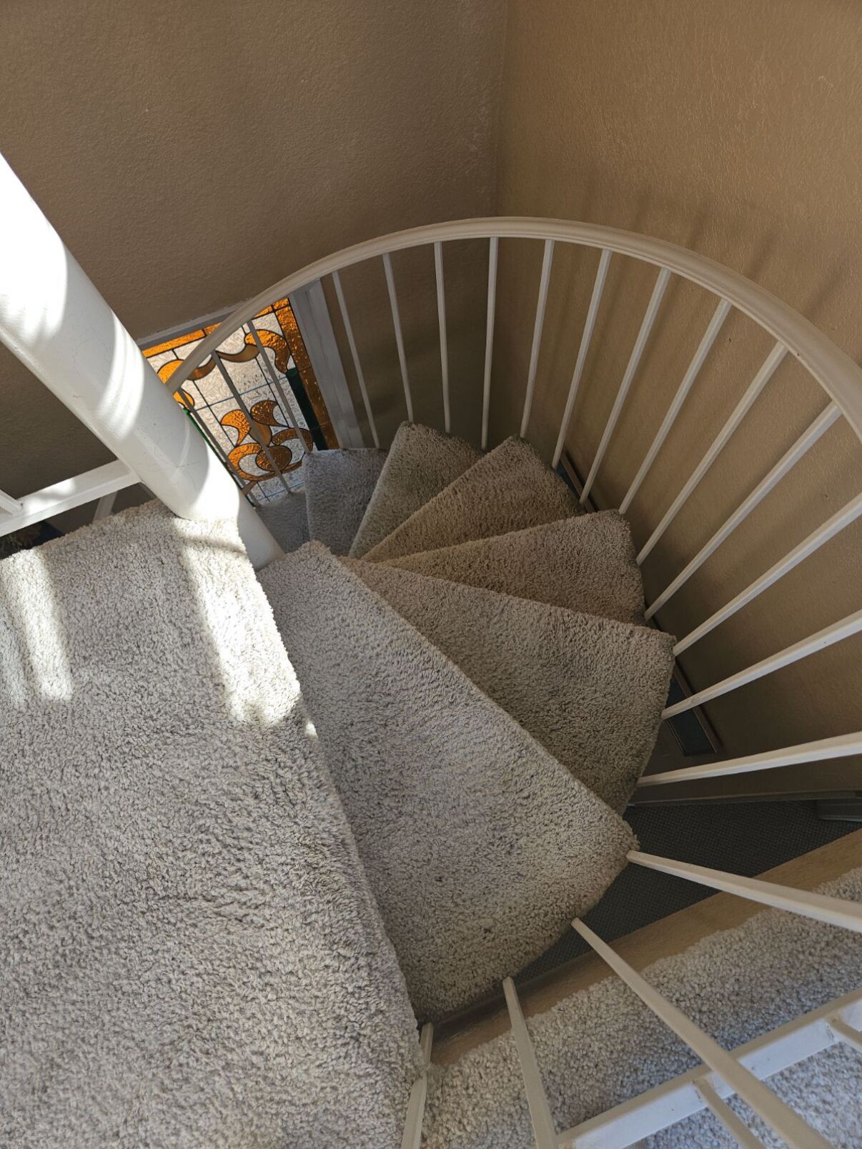 Eine Wendeltreppe mit Teppichstufen und weißen Geländern.