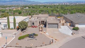 A residential area with a large house featuring a patio with a horse statue, surrounded by a landscaped garden.