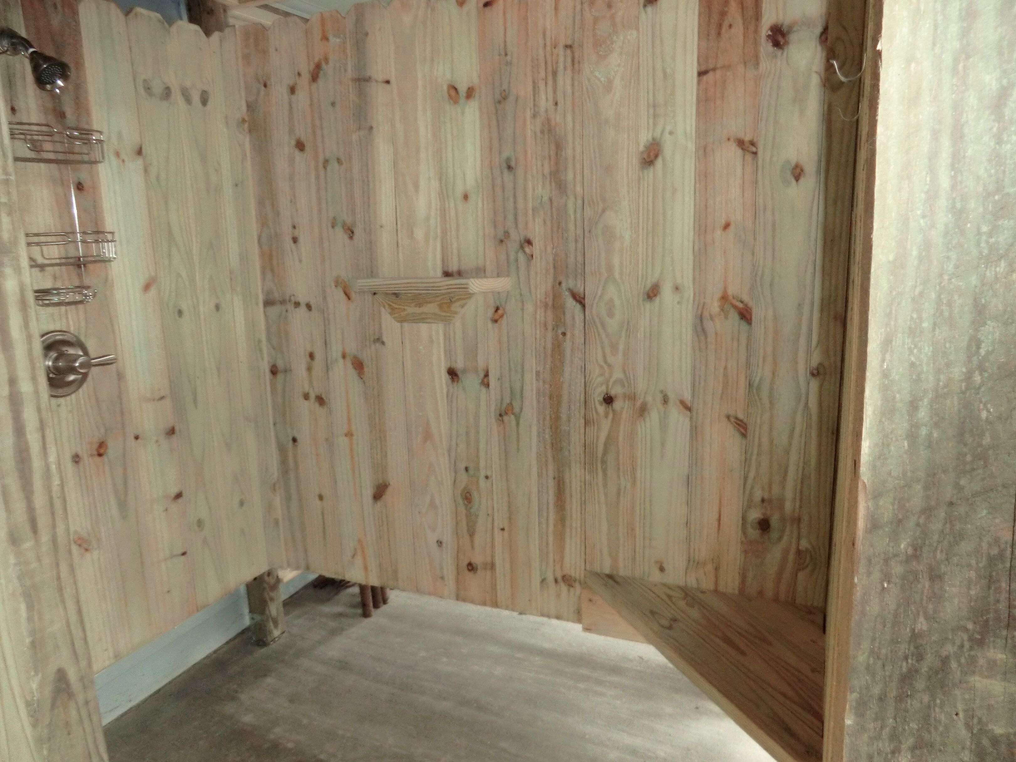 Ein Zimmer mit Holztür, einer kleinen Ablage und einem Betonboden.