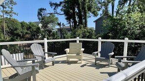 Een terras met Adirondack-stoelen en een bankje, omringd door een witte balustrade.