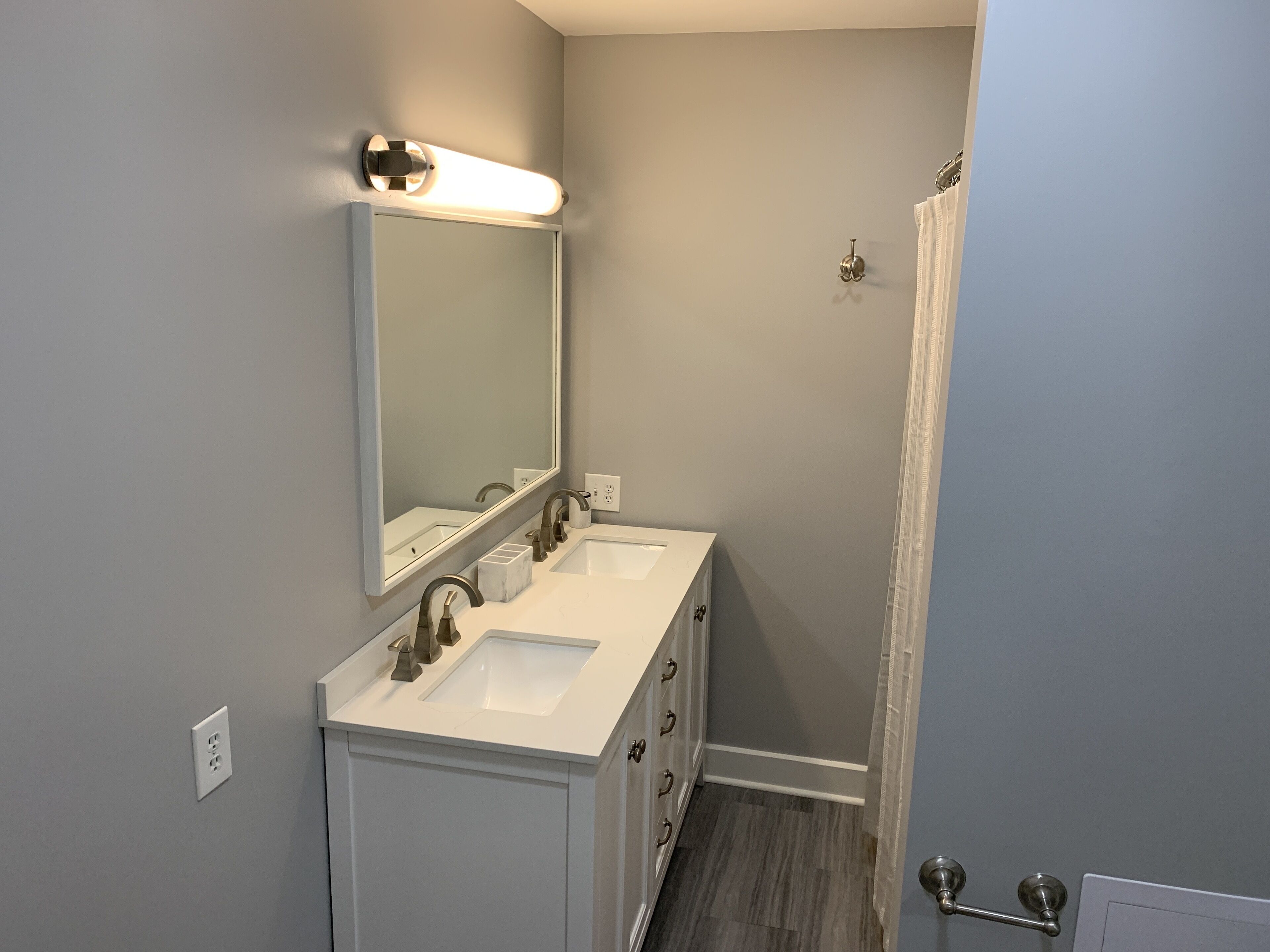 Une salle de bain avec deux lavabos, un grand miroir et un rideau de douche.