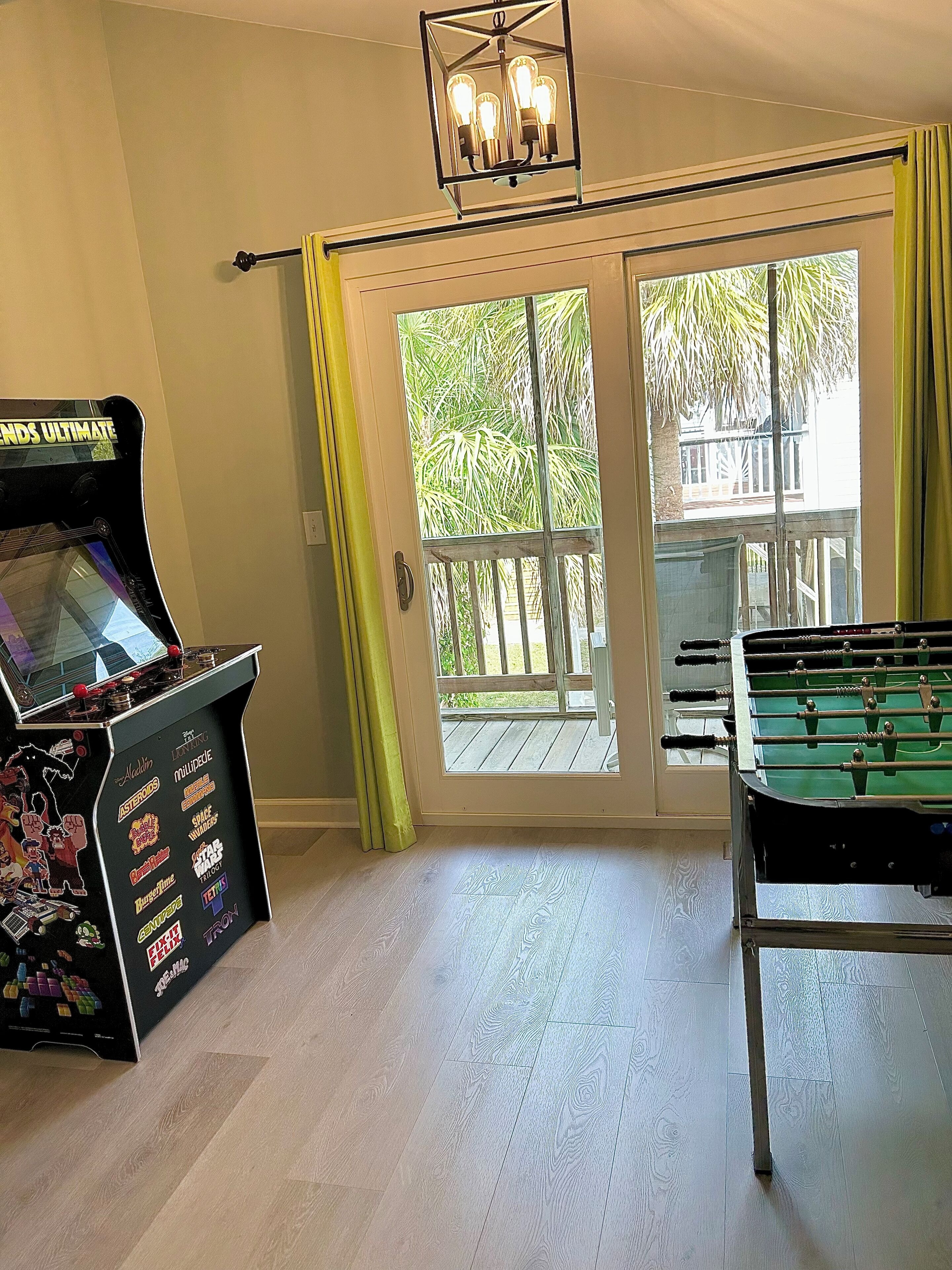 A room with a foosball table, a foosball table with a Star Wars theme, and a foosball table with a Space Invaders theme.