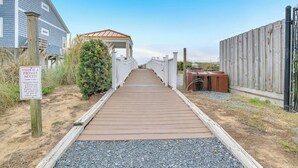 A wooden pathway leading to a covered structure with a sign indicating private access. - The Dunes: Ocean View Condo with Community Pool, Hot Tub, Beach Access (Oak Island)