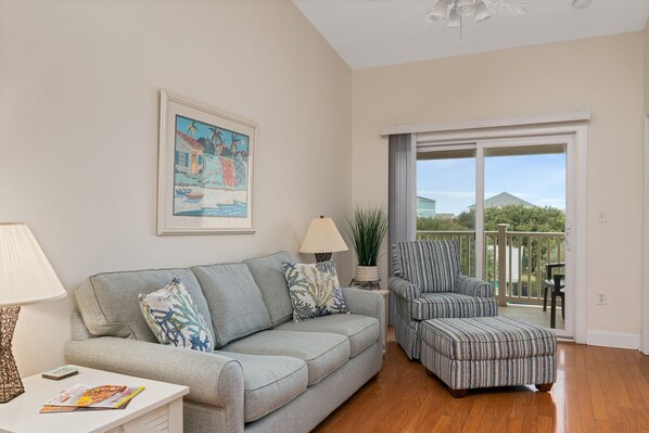 A living room with a grey sofa, striped armchair, and a potted plant.