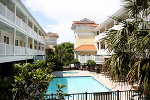 A hotel with a swimming pool, multiple balconies, and lush greenery.