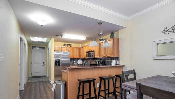 A modern kitchen with wooden cabinets, a stainless steel refrigerator, and a bar area with stools. - Luxury Riverfront spacious condo in perfect location near Tanger Outlets  (Sevierville)