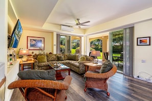 Relax in a spacious living area with a comfortable sectional sofa, wicker chairs, and a flat-screen TV.