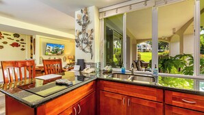 Una cocina con armarios de madera, encimera de granito y un amplio ventanal con vistas al exterior.