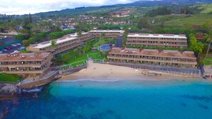 A beachfront hotel with multiple buildings, a sandy beach, and clear blue waters.