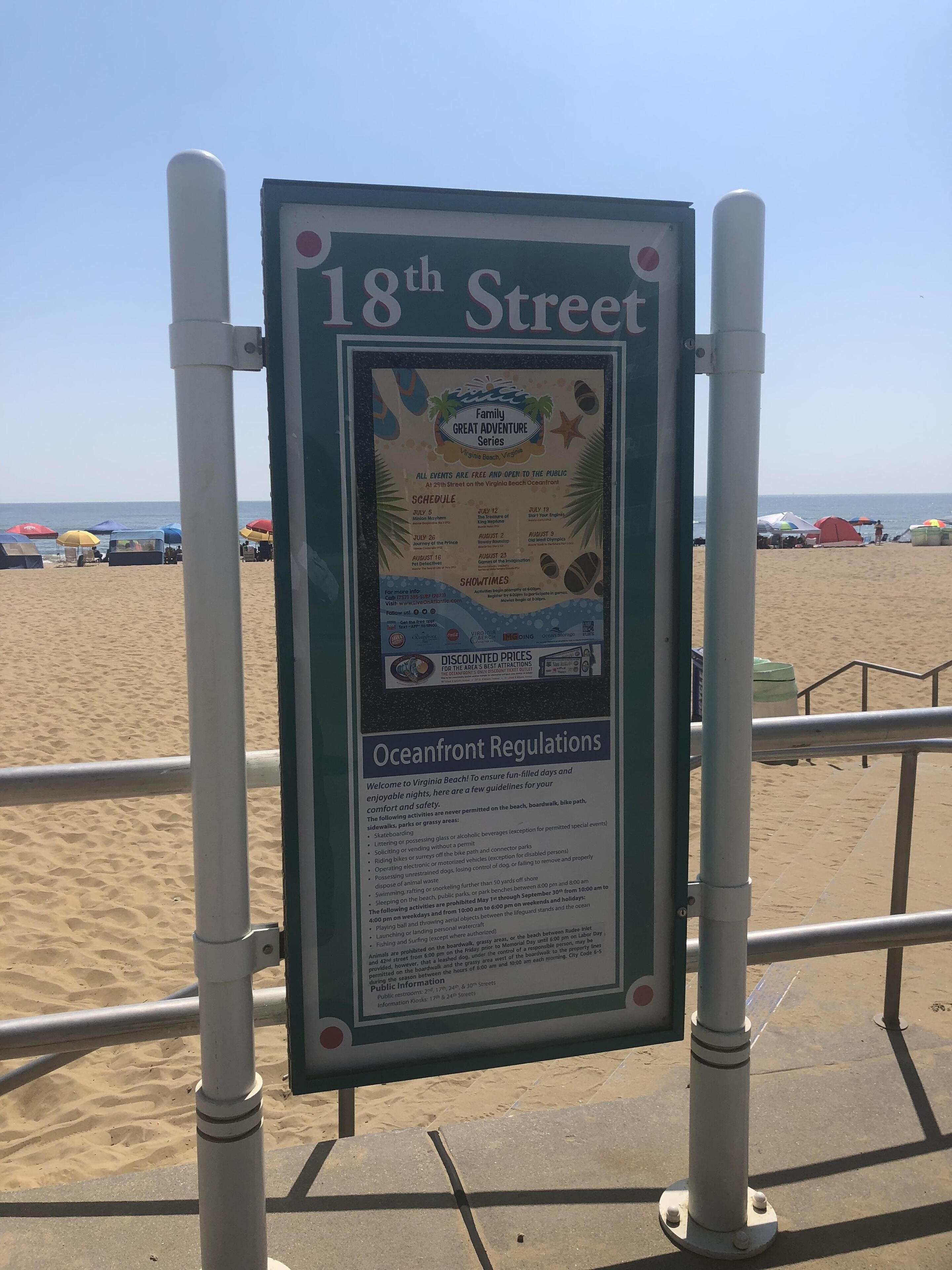 Un letrero de playa con la dirección '18th Street' e información sobre las normas y eventos de la playa.