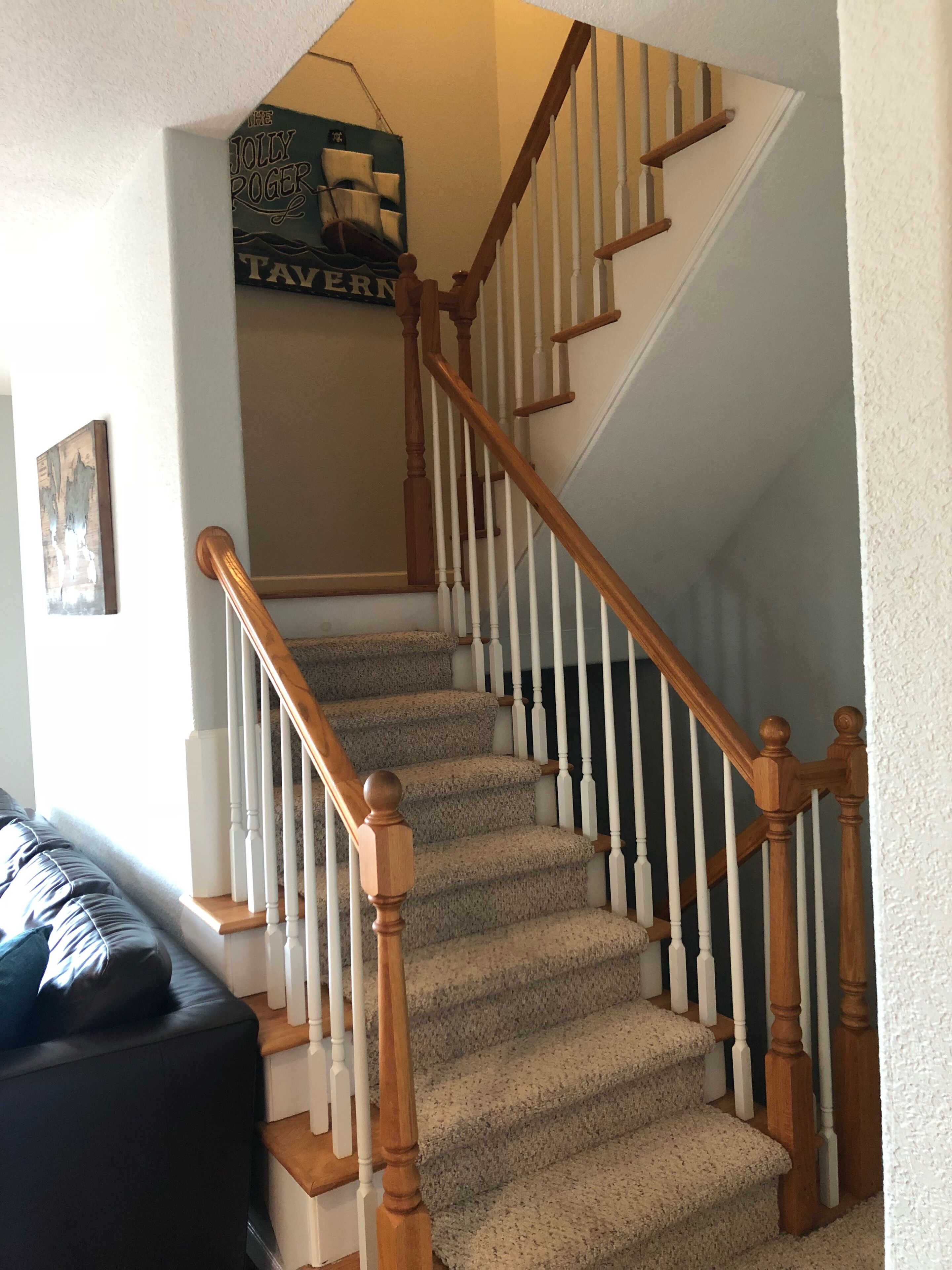 A staircase with wooden railings and carpeted steps leading to a landing.