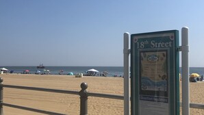 A beach scene with a sign for '18th Street' and a boat in the water.