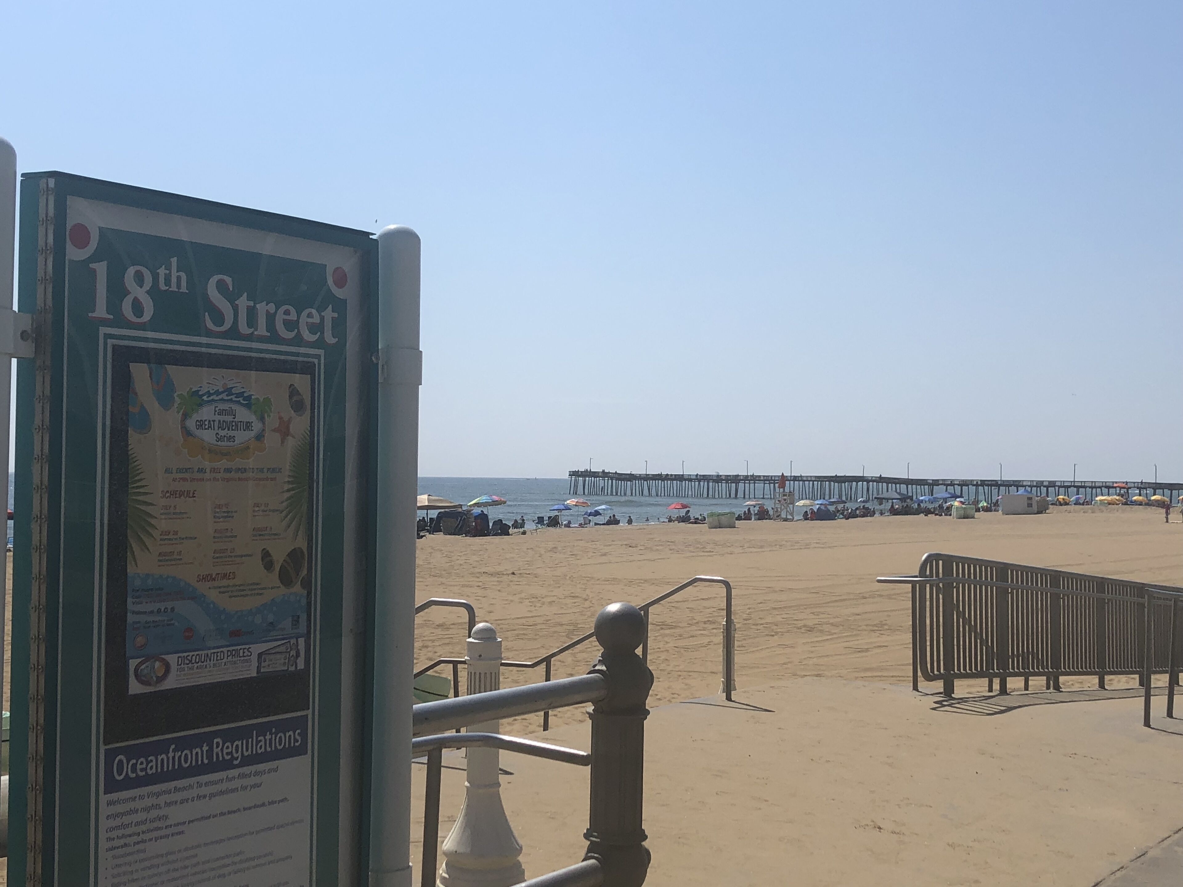 Een bord aan het strand met informatie over de 18th Street Family Great Adventure Series, inclusief tijden en gereduceerde prijzen.