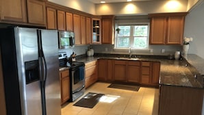 A modern kitchen with wooden cabinets, stainless steel appliances, and a granite countertop.