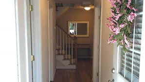 A hallway with wooden flooring, a staircase, and a door with a window.