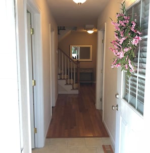 A hallway with wooden flooring, a staircase, and a door with a window.