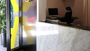 A reception desk with a computer, a chair, and a potted plant. - The Way Hotel (Busan)