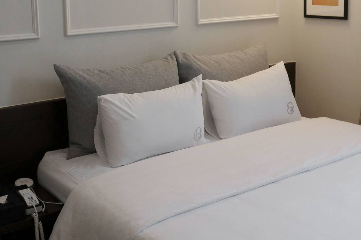 A hotel room with a bed, bedside table, and a wall-mounted light fixture.