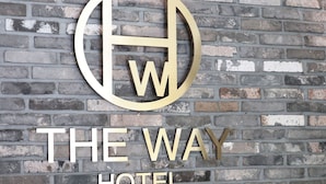 A reception desk with a sign that reads "THE WAY HOTEL" and a logo above it. - The Way Hotel (Busan)