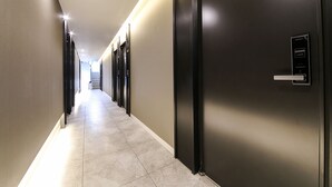 A modern hotel hallway with a long corridor, doors, and a card reader on the right wall. - The Way Hotel (Busan)