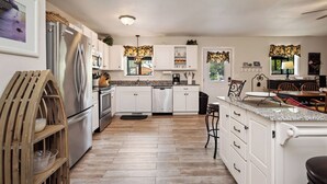 Una cocina moderna con armarios blancos, electrodomésticos de acero inoxidable y un banco de madera.