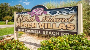 A beach-themed sign for Oak Island Beach Villas, including the address 1000 Caswell Beach Rd. - Garris Hideaway 2: Cozy 1st Level Oceanfront Condo - Perfect for Couples Getaway (Caswell Beach)