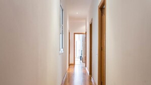 A narrow hallway with wooden flooring and light-colored walls.